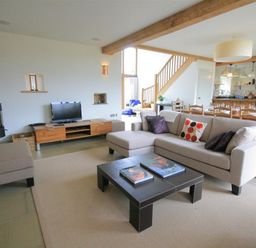 A living room with a sofa a coffee table a television and a wood stove next to a dining area at Stepwell in Moreton-In-Marsh