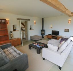 A living room with two sofas a coffee table a wooden cabinet a TV a small stove and an ottoman at Stepwell in Moreton-In-Marsh