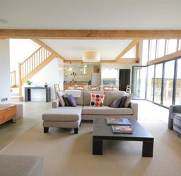 An open living room with a beige sofa, coffee table, staircase, and dining area at Stepwell in Moreton-In-Marsh