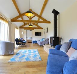 A living room with sofas a wood burning stove and exposed wooden beams at Park Stables Wyck Beacon near Bourton-on-the-Water