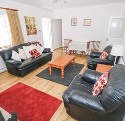 A living room with black leather sofas a wooden coffee table and a small dining table at Daffodil Cottage in Grange County Sligo