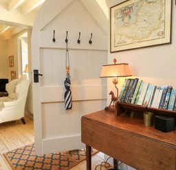 A living room with a desk books and a lamp at Cider Press Cottage in Priston Village, Bath