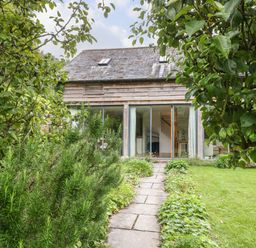 A garden path leading to a wooden house with large glass doors and skylights at The Cart Barn in Ridge near Chilmark
