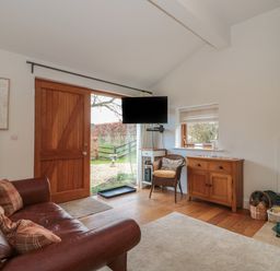 A living room with a leather sofa cushions a wood door and a mounted TV at Russet in Martin