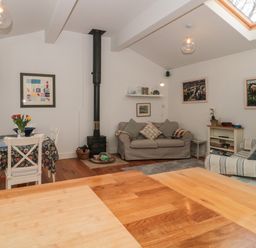 A living room with sofas a dining table with flowers a wood burning stove and paintings on the walls at Pippin in Martin