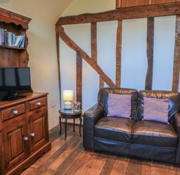 A living room with a sofa, television, and bookshelf at Pop's Barn in Downton