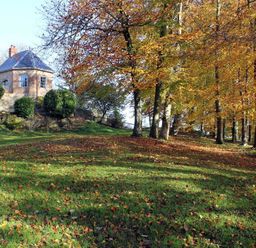A small stone house on a hill surrounded by trees with autumn leaves at The Folly at Castlebridge in Mere