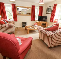 A living room with seating and a television at Droop Farm Cottage in Droop near Hazelbury Bryan