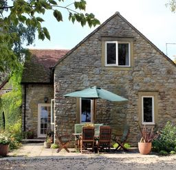 A stone house with outdoor seating at Droop Farm Cottage Droop near Hazelbury Bryan