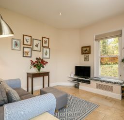 A sitting room with a sofa a wooden table and framed pictures on the wall at West Lodge in Rockbourne