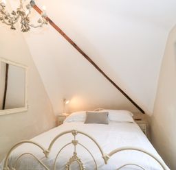 A bedroom with a bed a mirror on the wall and a window with curtains at Cosy Cot in Stapleford