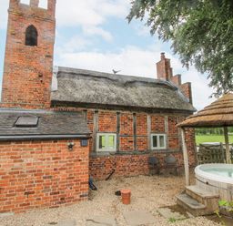 An outdoor area with a brick building and a hot tub at The Shooting Folly in Cheswardine