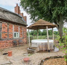 An outdoor area with a hot tub and seating at The Shooting Folly in Cheswardine