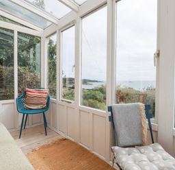 A conservatory with windows and seating at Greeb Rocks Cottage in Marazion