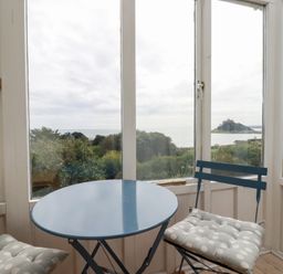 A table and chairs in a conservatory with a sea view at Greeb Rocks Cottage Marazion