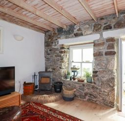 A living room with a wood stove and a television at Greeb Rocks Cottage in Marazion