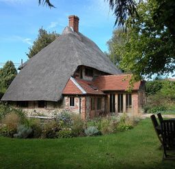 A thatched roof cottage with garden and outdoor seating at The Yeomans House in Bignor