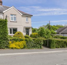 An exterior view of a semi detached house with a hedge and a garden in front at Arnant in Dolgellau
