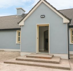 Exterior view of a blue house with a small porch and steps leading to an open door at Dromstabla in Glencar