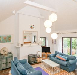 A living room with two blue sofas a white coffee table a fireplace and hanging lights at The Schooner in Goleen County Cork