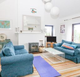 A living room with two blue sofas a white coffee table a wood stove a television and a yoga mat at The Schooner in Goleen County Cork