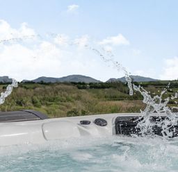 A hot tub with water jets and a countryside view at Hen Hafod in Talwrn near Llangefni
