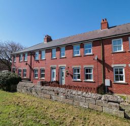 A row of red brick terraced houses with white framed windows and small front yards at The Tannery in Whitby