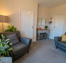 A room with two leather chairs a table lamp a wooden side table with mirror and two white doors at The Tannery in Whitby