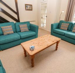 A living room with two teal sofas and a wooden coffee table at The Chace in Portreath