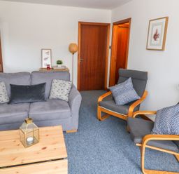 A sitting room with a gray sofa and two armchairs with cushions at Kestrel Lodge in Dumfries