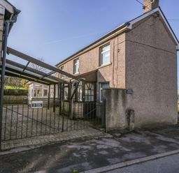 A two-story house with a gravel driveway and a black metal gate at Rose Cottage in Bream