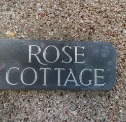 A sign reading Rose Cottage mounted on a rough pebbled wall at Rose Cottage in Bream