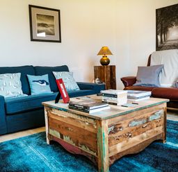 A living room with blue sofa brown armchair and wooden coffee table at Oystercatcher Embleton