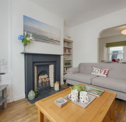 A living room with a grey sofa and a wooden coffee table with cups a teapot and a book at Anchorage in Watchet