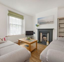A living room with two grey sofas a wooden coffee table a fireplace and a window with a green blind at Anchorage in Watchet