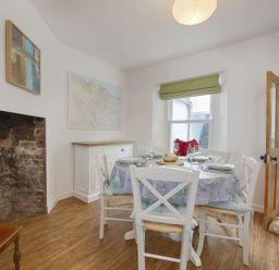 A dining room with a round table set for four chairs a sideboard and a window at Anchorage Watchet
