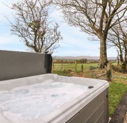 An outdoor hot tub with water bubbling near grass and trees at Bwthyn Lan in Boncath