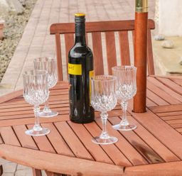 A wooden outdoor table with four crystal wine glasses and a bottle of wine in a garden setting at Cnoc suan in Aughavas County Leitrim