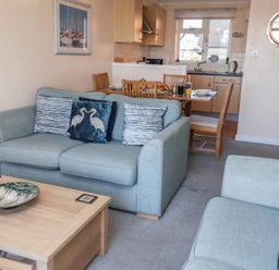 A living room with a sofa and dining area at Daisy Lodge in Norwich