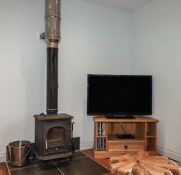 A living room with a stove and television at The Smithy in Blisland