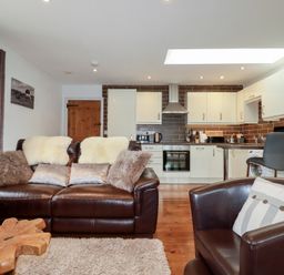 A living room with a sofa and kitchen area at The Smithy in Blisland