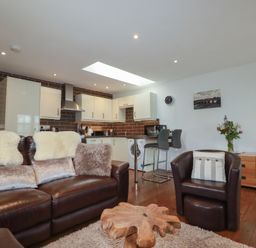 A living room with a sofa and kitchen area at The Smithy in Blisland