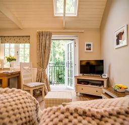 A living room with a table and chairs a tv on a stand and an open door leading outside at Lime Tree in Burford