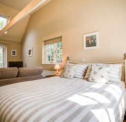 A bedroom with a bed a sofa nightstands lamps and a window at Lime Tree in Burford