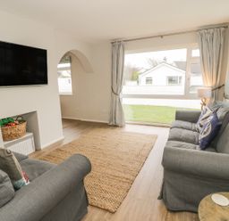 A living room with two grey sofas and a large window at Ty Taid in Rhosneigr