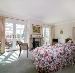 A living room with floral sofa a fireplace and glass doors at Sheilas Cottage in Penryn