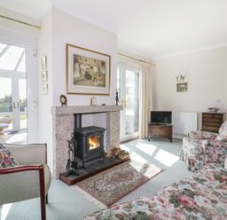 A living room with a fireplace armchairs and a floral sofa at Sheilas Cottage in Penryn