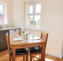 A kitchen dining area with a wooden table set for two near windows at Aln in Longframlington
