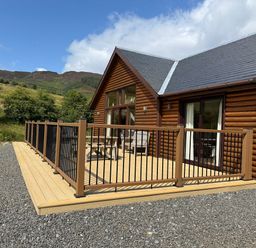 A log cabin exterior with a wooden deck at Burnside Lodge (Lodge 1, Glengoulandie) Aberfeldy