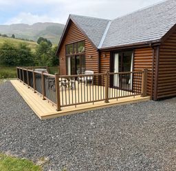 A log cabin with decking and chairs at Burnside Lodge (Lodge 1, Glengoulandie) Aberfeldy